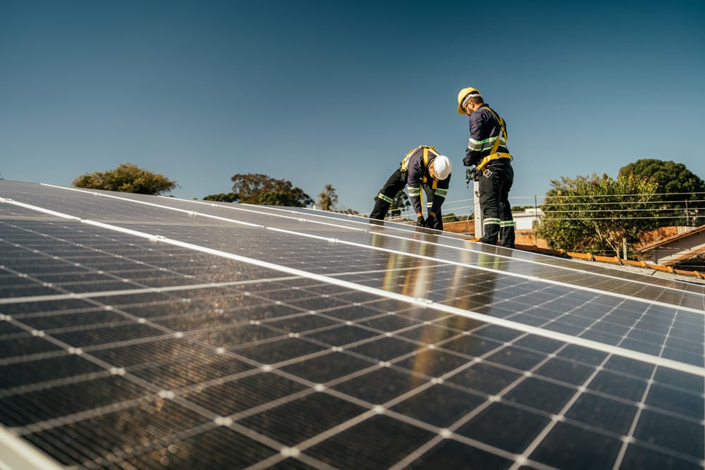 two construction workers installing solar panels in a solar farm